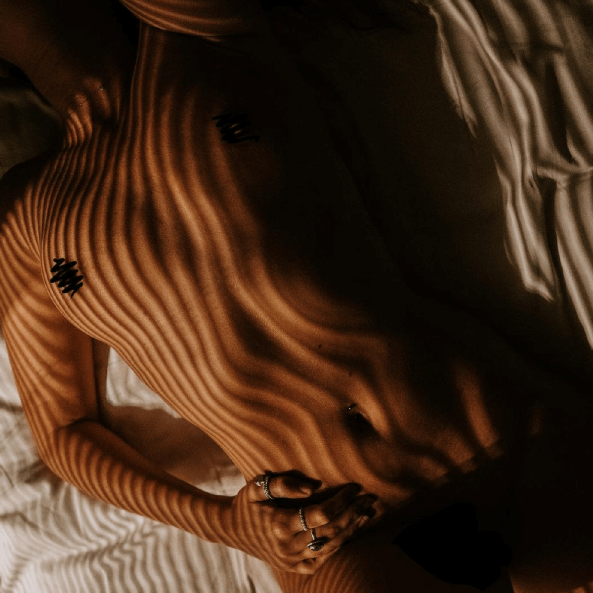Woman lying down naked on bed